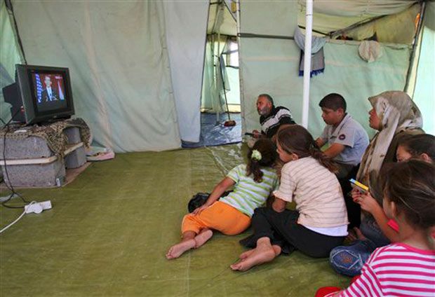 A Palestinian family, whose home was lost after Israel's incursion in Gaza, watches the speech from a tent in Gaza City.